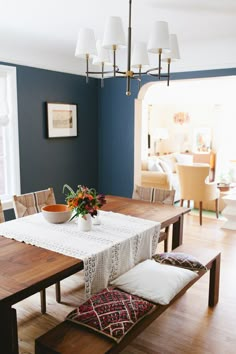 a dining room table and bench with flowers on the centerpiece in front of it