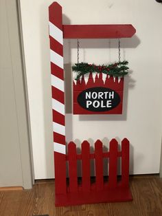 a red and white sign hanging from the side of a wall next to a wooden fence