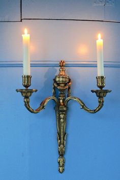 two lit candles are attached to the wall