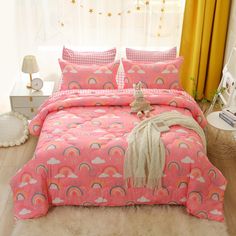 a pink bed with rainbows, clouds and stars on the comforter is next to a window