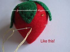 a red strawberry ornament with green leaves on it and needles in the middle