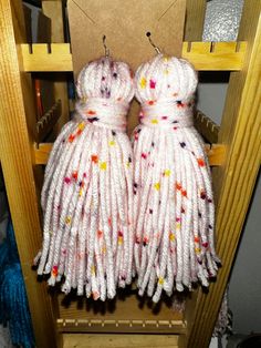 two white dresses made out of yarn sitting on top of a shelf