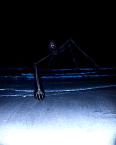 a creepy figure is standing in the dark with his arms spread out and eyes open