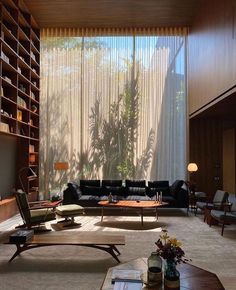 a living room filled with furniture next to a window covered in sheer curtained drapes