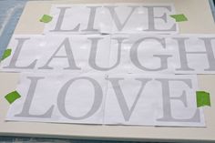 the words live laugh love are cut out on white paper with green adhesive tape