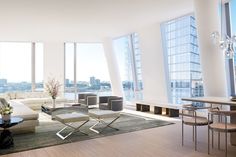 a living room filled with furniture next to tall window covered walls and floor to ceiling windows