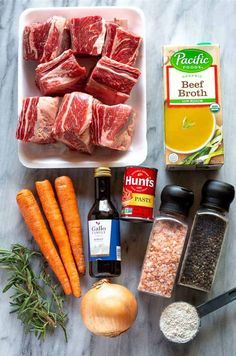 meat, spices and seasonings laid out on a marble counter top next to carrots