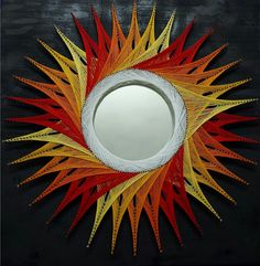 a circular mirror with red, yellow and orange strips on it's face in front of a black background