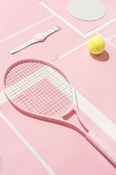 a tennis racket and ball on a pink surface