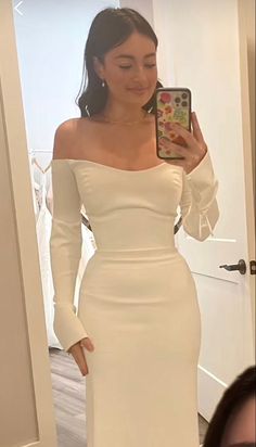 a woman in a white dress taking a selfie