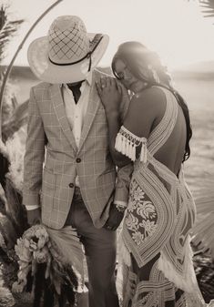 a man in a suit and hat standing next to a woman wearing a long dress