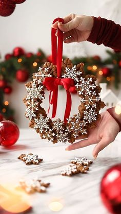 a person holding a christmas wreath ornament in their hand