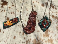 "Hand tooled and painted leather pendant necklaces to spice up that cowgirl style. The sunflower bar is on a 19\" chain. The faux turquoise painted southwest inspired pendant is on a 26\" chain. The natural freshwater pearl and classic western floral pendant is on a 24\" chain. All ready to ship and what's pictured is what you will receive." Southwestern Style Hand Tooled Necklace As Gift, Western Stamped Brown Jewelry, Western Style Stamped Brown Jewelry, Western Brown Stamped Jewelry, Handmade Western Style Necklace, Artisan Brown Hand Painted Necklace, Artisan Hand Painted Brown Necklace, Native American Headdress, Leather Pendant