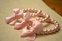 three pink bows and pearls on a table