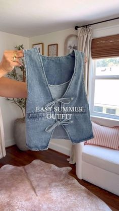 a woman is holding up an old jean vest