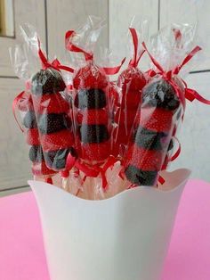 chocolate covered strawberries wrapped in cellophane and tied with red ribbon on pink table