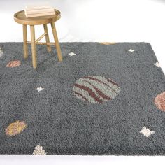 a gray rug with various designs on it and a small wooden table in the background