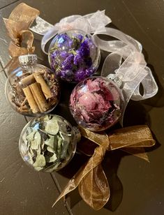 four glass ornaments with ribbons and bows on the top one is filled with dried flowers