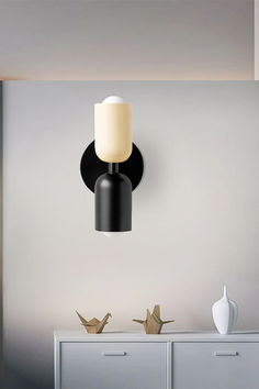 a black and white lamp hanging on the wall next to a dresser in a room