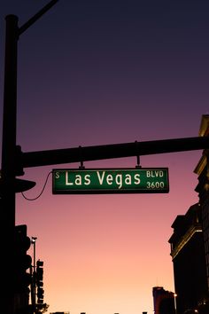 the street sign for las vegas blvd is lit up at night with buildings in the background