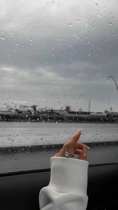 a person's hand on the dashboard of a car in front of a large body of water