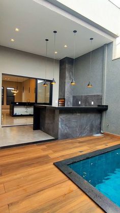 an indoor swimming pool in the middle of a room with wood flooring and gray walls