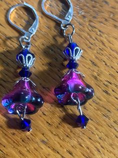 These handmade earrings are made from very special flower shaped beads.  These Purple amethyst and blue glass flowers shine like crystals with overlapping colors.  The earrings measure 2inches in length to the bottom of the blue crystal and have a lever back closure.  If you prefer a wire closure please message me. Czech Glass Dangle Flower Earrings With Ear Wire, Flower-shaped Beaded Czech Glass Earrings, Purple Czech Glass Earrings For Gift, Unique Purple Earrings With Dangling Beads, Purple Flower Earrings For Party With Ear Wire, Nickel-free Purple Glass Jewelry, Purple Flower Shaped Earrings, Elegant Blue Czech Glass Flower Earrings, Czech Glass Dangle Earrings With Bead Caps