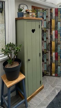 a potted plant sitting on top of a wooden stool next to a green cabinet