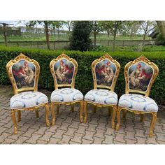 four chairs with paintings painted on them sitting in front of a hedged area and bushes