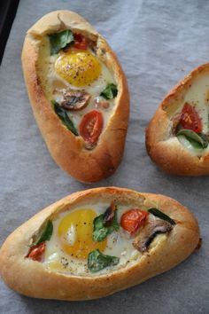 three bread bowls with eggs and vegetables in them