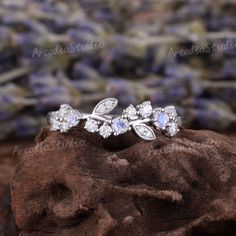 an image of a ring with stones on it and lavender flowers in the back ground