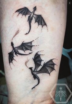 two black bats flying in the air with their wings spread out, tattoo design on leg