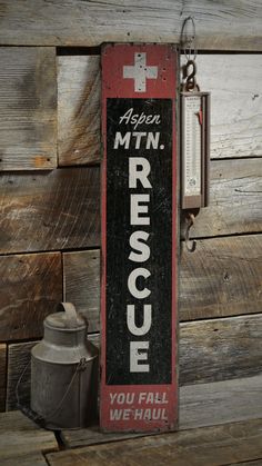 an old red rescue sign hanging on the side of a wooden wall next to a watering can