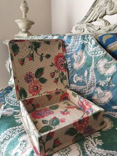 an open box sitting on top of a bed next to a white wooden headboard