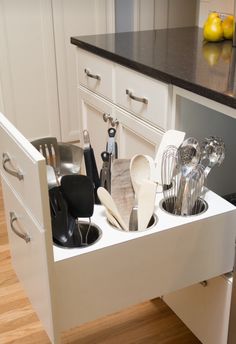 an open drawer in the middle of a kitchen with utensils and spoons