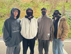 four people in hoodies standing next to each other with masks on their faces and one person wearing a face mask