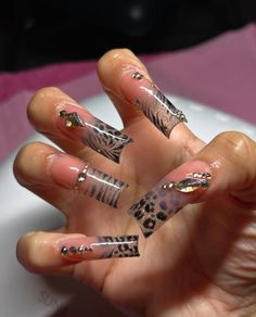 a person holding their hand with some animal print on it and nail designs on the nails