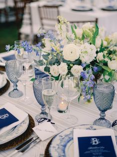 the table is set with blue and white plates, silverware, and flowers in vases