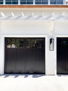 two black garage doors in front of a white house