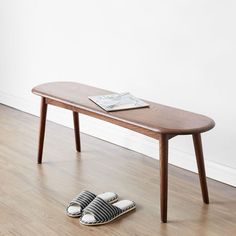 a pair of slippers sitting on the floor next to a wooden table with a magazine on it