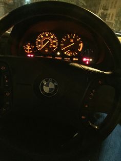 the dashboard of a bmw car is lit up with red and yellow lights at night