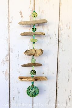 a wind chime made out of driftwood and glass beads on a white wall