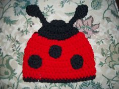 a crocheted ladybug hat sitting on top of a bed