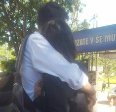 two people are hugging each other in front of a bus station sign that reads,