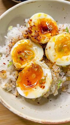 three fried eggs on top of rice in a bowl