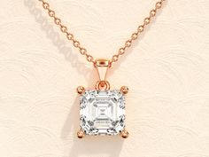 a necklace with a square cut diamond in the center on a gold plated chain