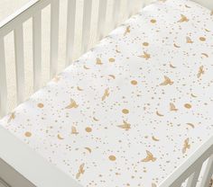 a white crib with gold stars and moon prints on the sheet in front of it