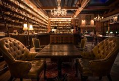 a dimly lit bar with leather chairs and chandeliers