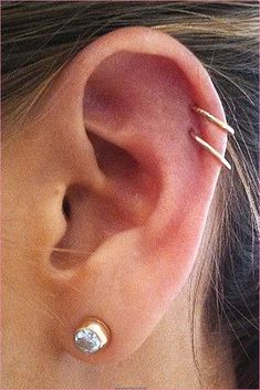 a close up of a person's ear with two small piercings on it