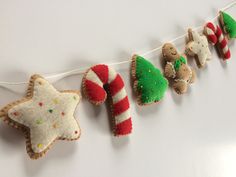 christmas decorations hanging from a string on a white wall with candy canes and cookies